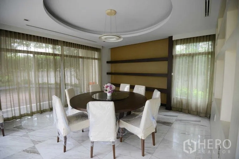 Detached House for sale in Bang Kapi, Bangkok - Dining room with round table, statement ceiling light and marble flooring beside large windows