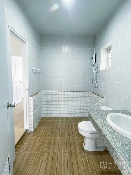 Detached House for rent in Lam Luk Ka, Pathum Thani - Clean bathroom with tiled walls, granite counter and shower water heater.