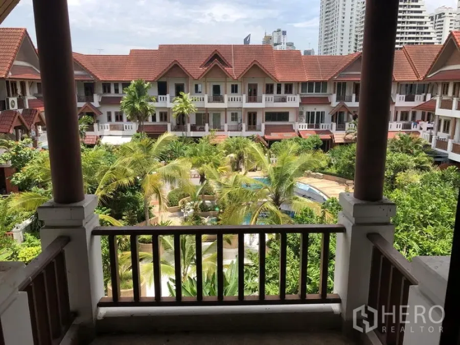 联排别墅 出租或出售在Watthana, Bangkok - 阳台俯瞰热带中央花园和公共泳池，周围为红屋顶联排别墅