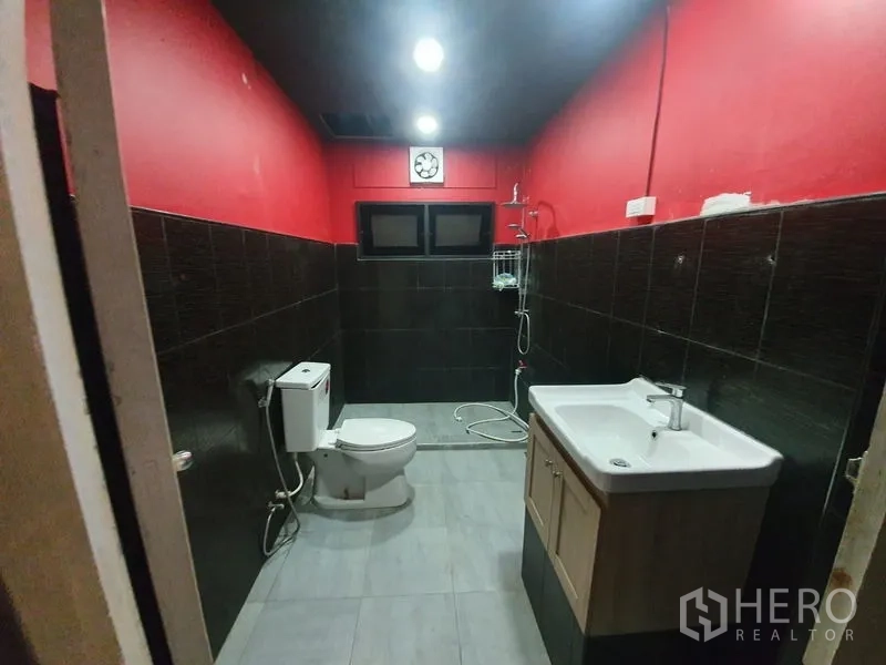店屋 出租在Khlong Toei, Bangkok - 浴室配红色墙、黑色瓷砖，设淋浴、马桶和洗手台。