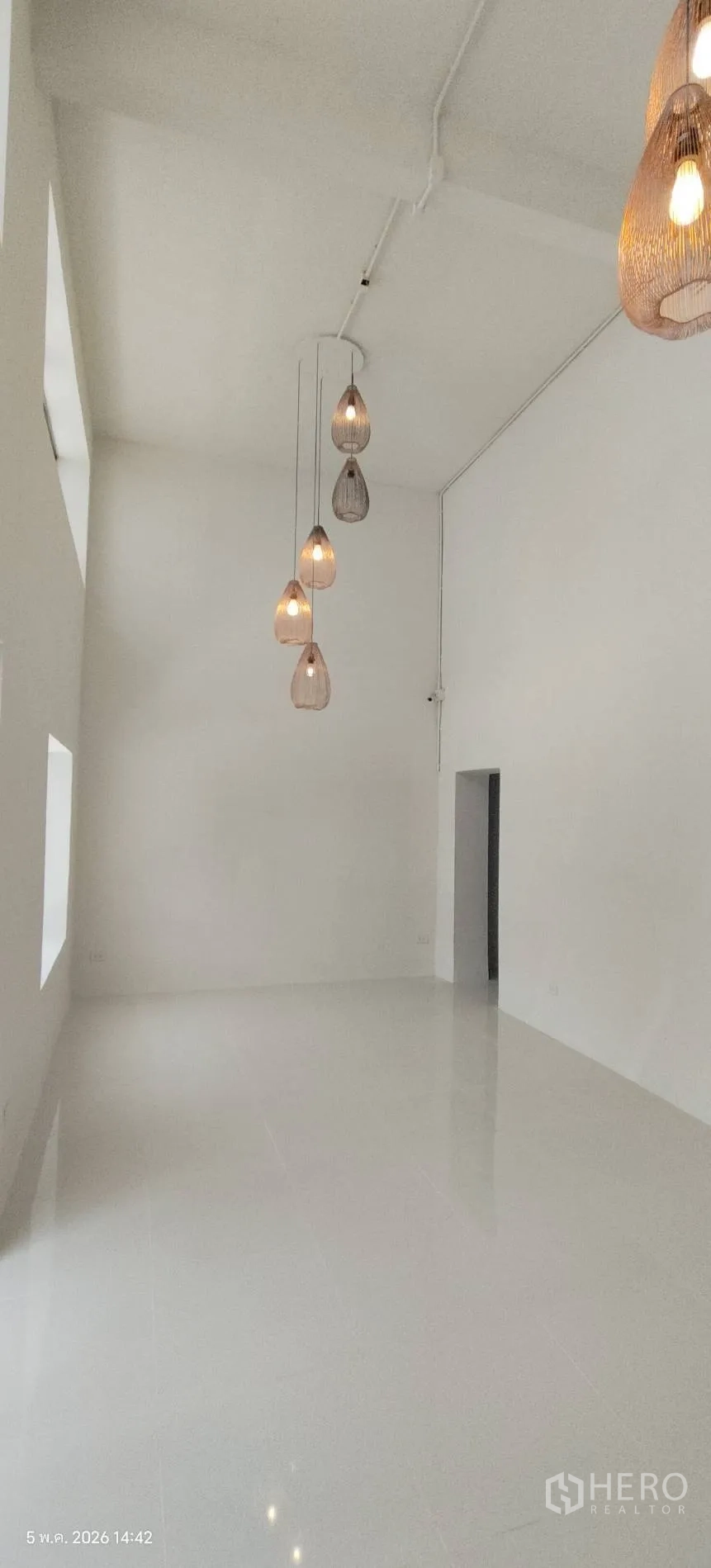 Shophouse for rent in Watthana, Bangkok - Double-height showroom with white walls and pendant lights.