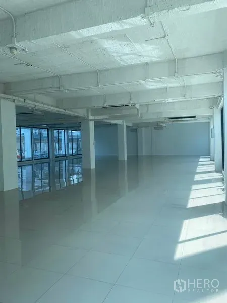 Office Space for rent in Khlong Toei, Bangkok - Open office area with rows of windows, sunlight streaming in, exposed piping ceiling and glossy floor.