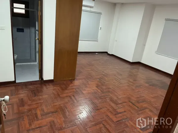 独立式住宅 出租在Watthana, Bangkok - 室内大房间，拼花木地板、白色墙面，并有通往套卫的门。