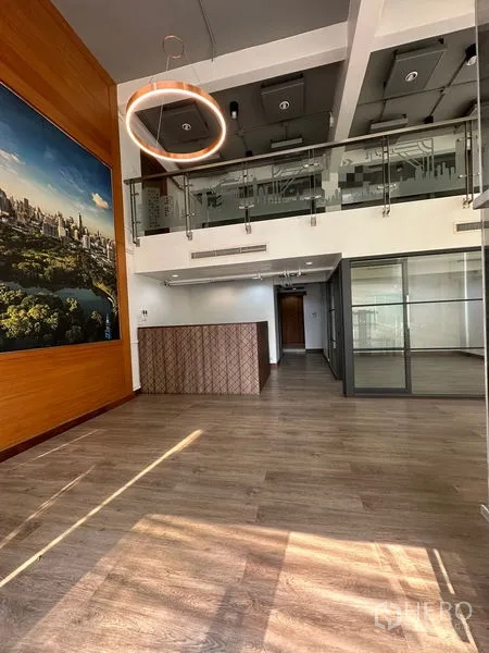 Office Space for rent in Pathum Wan, Bangkok - Reception area with wood accents, large wall art and a mezzanine glass railing inside the office.