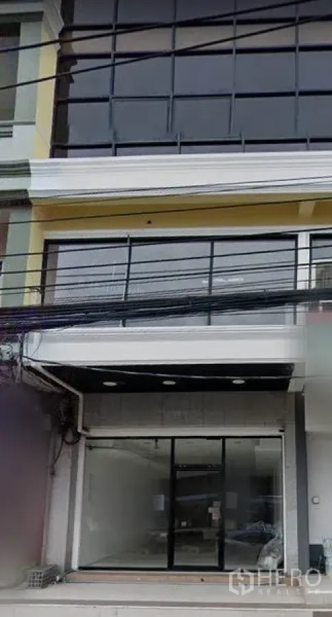 Shophouse for rent in Khlong Toei, Bangkok - Modern shophouse facade with large glass windows and sliding entrance near On Nut BTS.