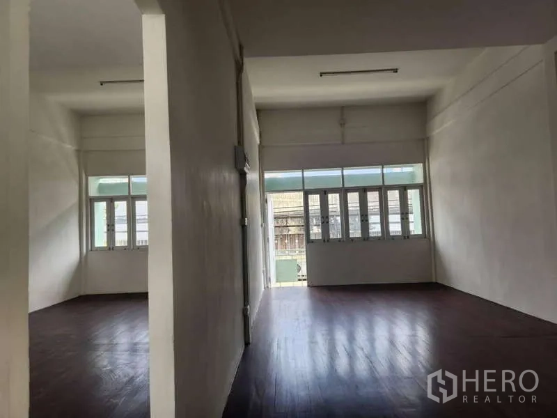 Shophouse for rent in Khlong Toei, Bangkok - Two partitioned upper rooms with large windows and wood floors.
