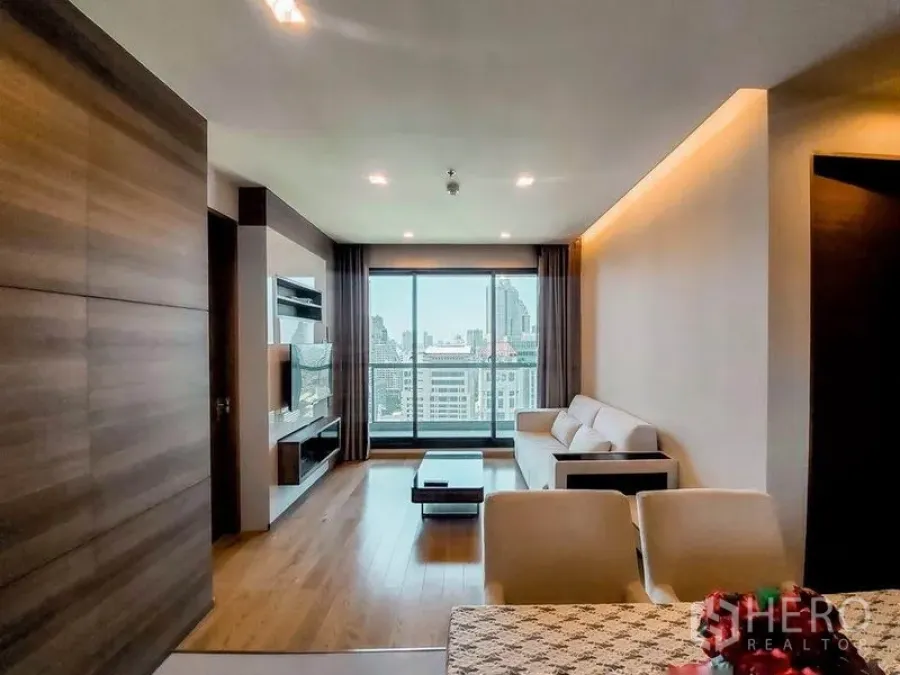 Condominium for rent in Bang Rak, Bangkok - Spacious living area facing a wide window wall and balcony, capturing sweeping Bangkok skyline views.