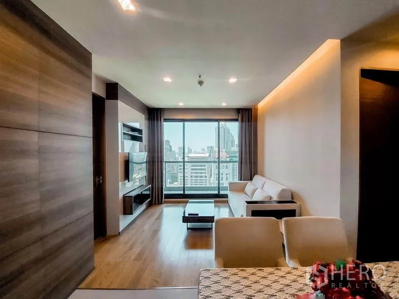 Condominium for rent in Bang Rak, Bangkok - Spacious living area facing a wide window wall and balcony, capturing sweeping Bangkok skyline views.