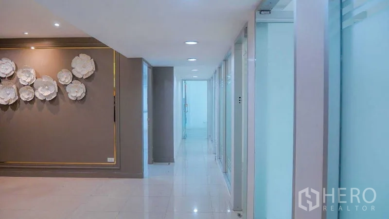 Office Space for rent in Chatuchak, Bangkok - Well‑lit corridor leading to glass‑partitioned offices with recessed ceiling lights and glossy flooring.