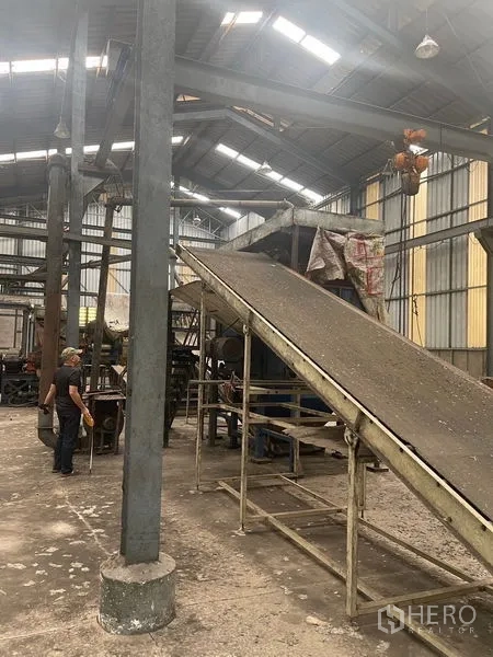 Warehouse for rent or sale in Bang Bon, Bangkok - Industrial conveyor and machinery inside a high-roofed warehouse space.