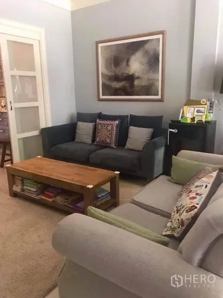 Townhouse for rent or sale in Bangkok - Cozy living room with grey sofas, wooden coffee table and sliding door in a Bangkok townhouse.