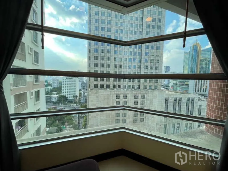 Apartment for rent in Khlong Toei, Bangkok - City view framed by angular bay windows from the living room.