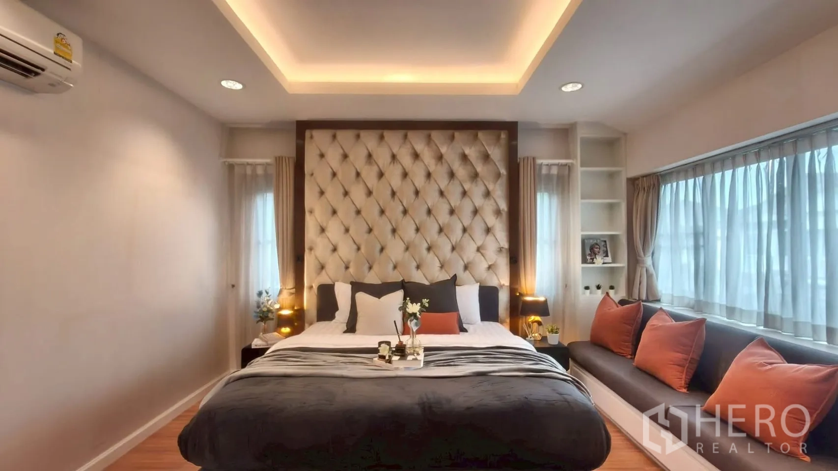 Detached House for rent or sale in Mueang Samut Prakan, Samut Prakan - Wide view of master bedroom with oversized tufted headboard, window bench with cushions and cove lighting.