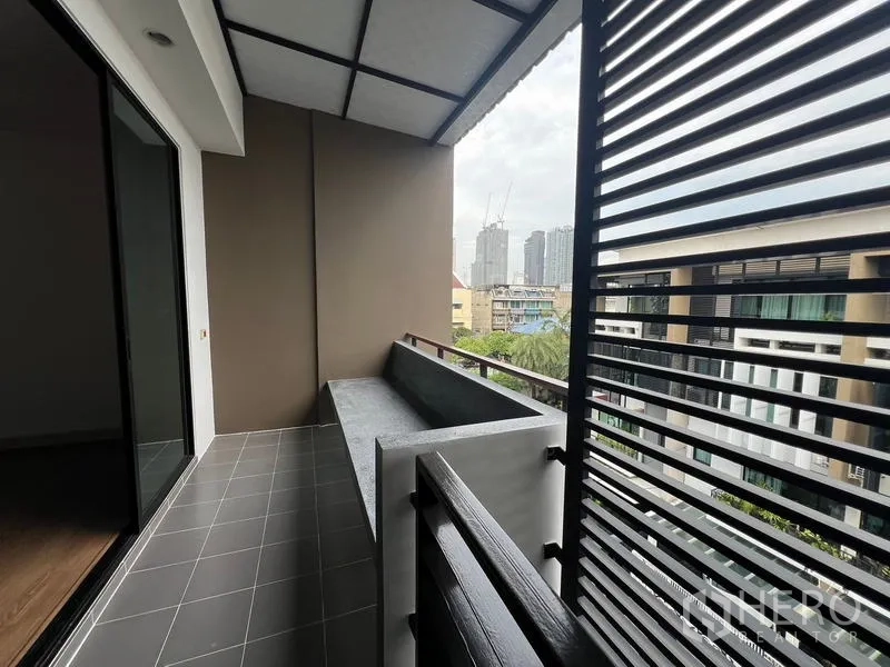 Townhouse for rent or sale in Khlong Toei, Bangkok - Balcony with privacy louvers and city views toward the Sukhumvit skyline.
