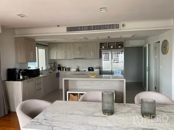 Condominium for rent in Sathon, Bangkok - Close-up of contemporary L-shaped kitchen with island, built-in cabinetry and double-door refrigerator.