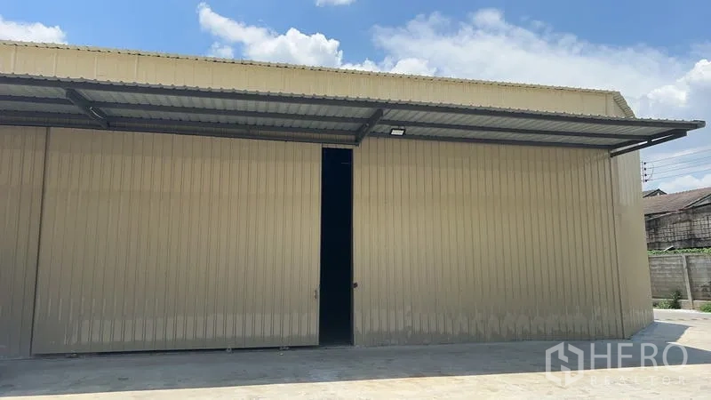 Warehouse for rent in Phra Khanong, Bangkok - Exterior close-up of a large sliding access door beneath the canopy on the metal-clad warehouse.