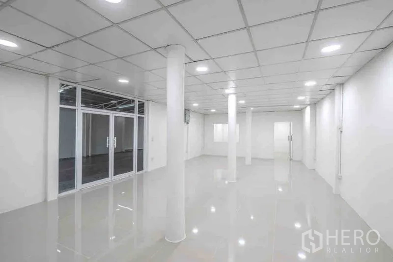 Standalone for rent or sale in Bang Na, Bangkok - Large open-plan hall with grid ceiling, round columns, and glass sliding doors.