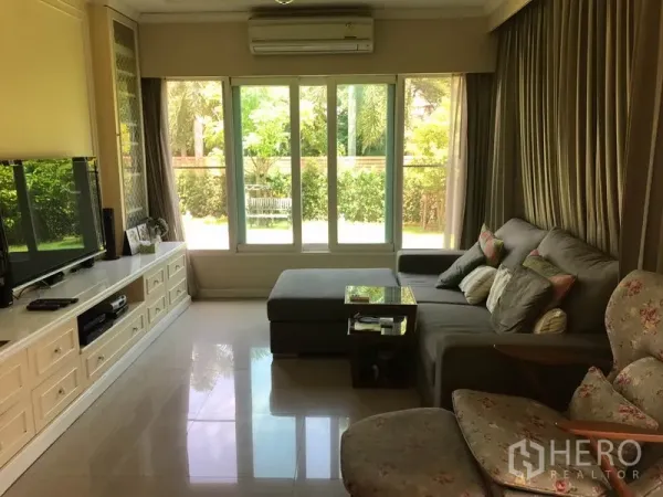 บ้าน ขายในPak Kret, Nonthaburi - โซนนั่งเล่นกว้าง โซฟา L‑shape กระจกเต็มผนัง มองออกสู่สวน