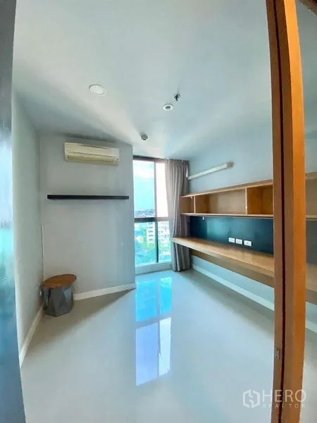 Condominium for rent in Chatuchak, Bangkok - Second bedroom or study with long built-in desk, shelves and a bright window view.