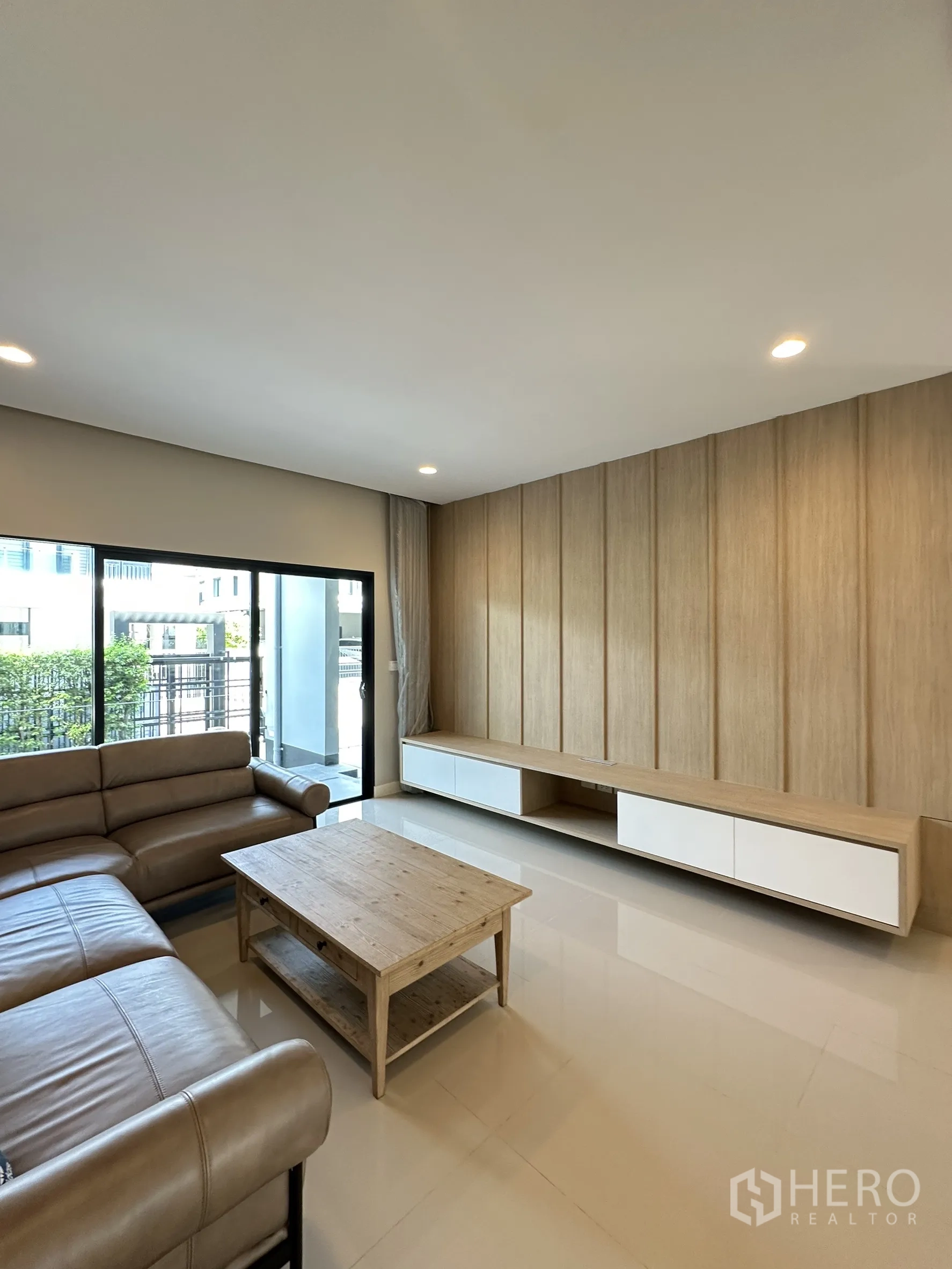 Detached House for sale in Lam Luk Ka, Pathum Thani - Living area with long built-in TV console and sliding glass doors opening to the patio.
