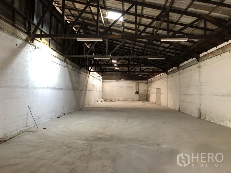 Retail Space for rent in Khlong Toei, Bangkok - Spacious warehouse-style retail interior with high steel truss ceiling, white walls, and a concrete floor.