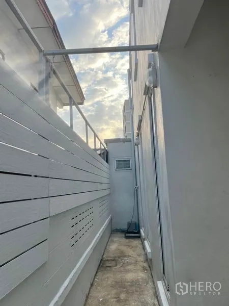 Detached House for rent in Huai Khwang, Bangkok - Narrow service walkway along the house with privacy fence and visible utility lines.