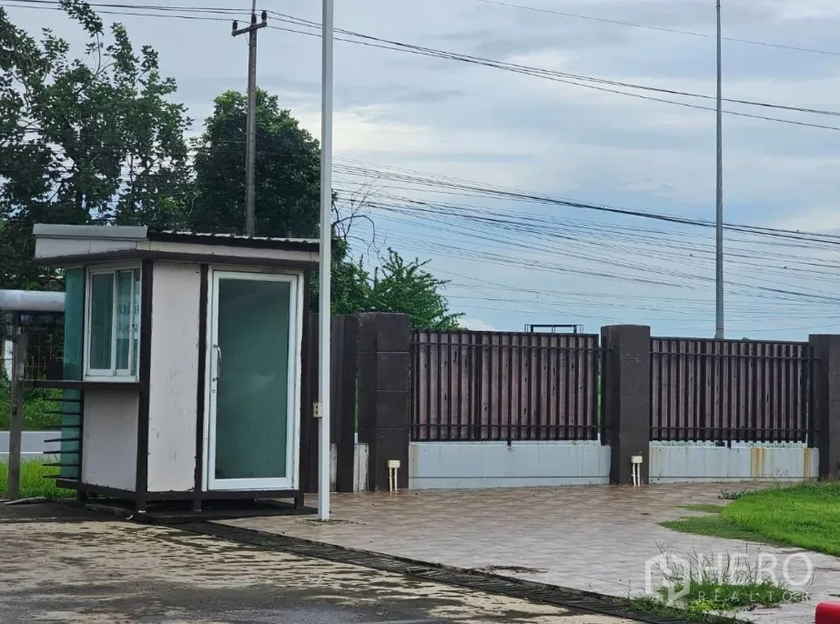 Warehouse for rent in Lam Luk Ka, Pathum Thani - Gated entrance with small guardhouse controlling site access.