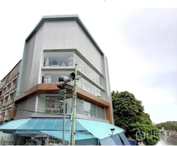 Shophouse for rent in Pathum Wan, Bangkok - Modern corner shophouse with full-height glass windows and a blue awning in Bangkok.