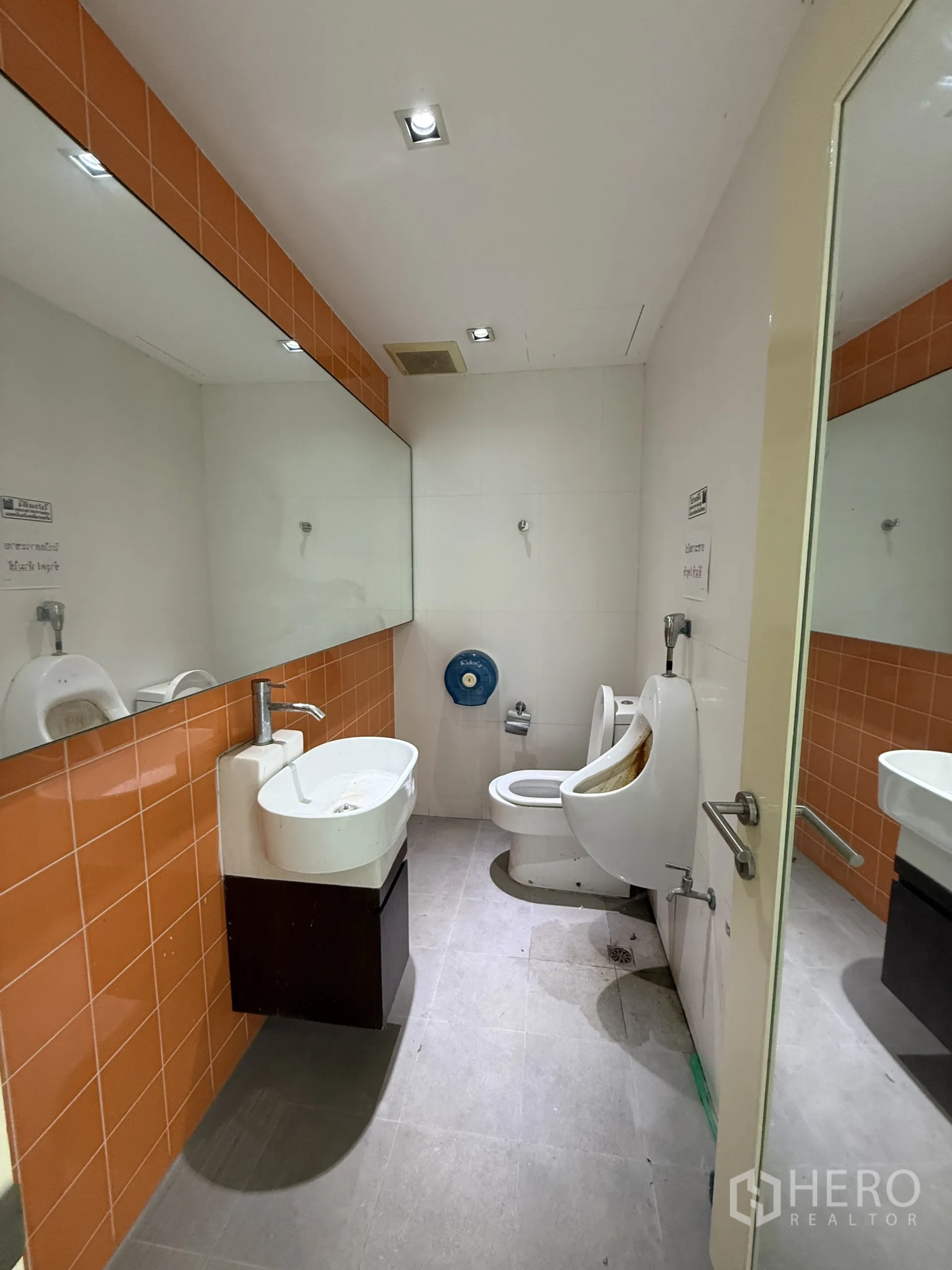 Retail Space for rent in Bang Rak, Bangkok - Men’s restroom with sink, mirror, orange wall tiles, urinal and toilet.