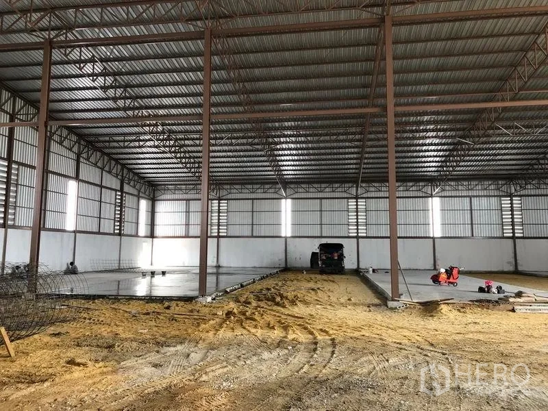 Warehouse for rent or sale in Sai Noi, Nonthaburi - Symmetrical warehouse hall with polished concrete sections and a sand base.