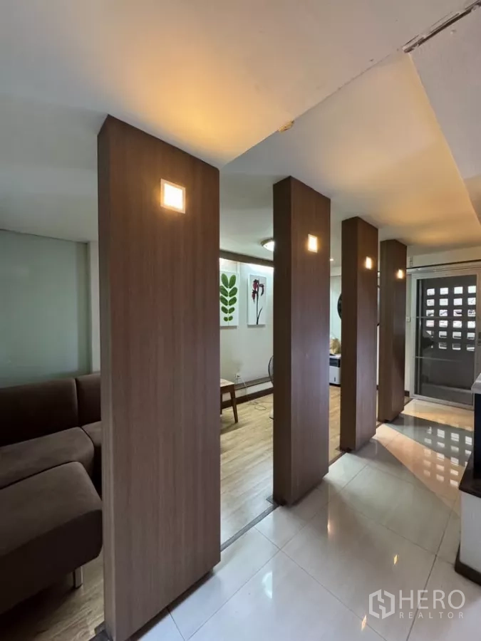 Shophouse for rent in Bang Rak, Bangkok - Hallway divided by vertical wooden columns with accent lights leading to a living area.