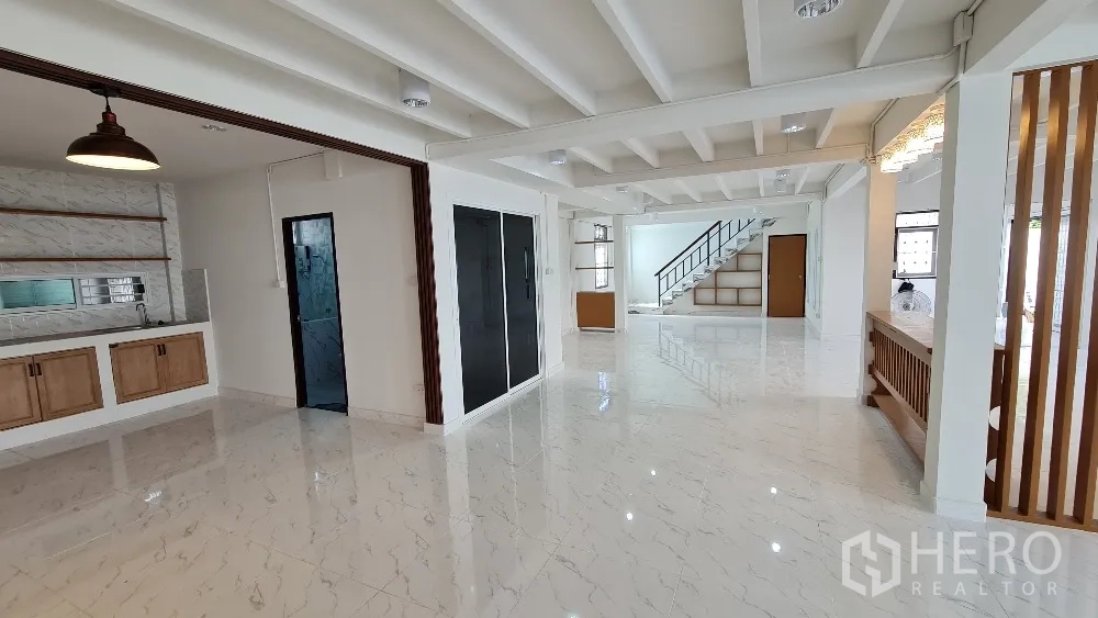 独栋房屋 for rent in Lat Phrao, Bangkok - 一层开放空间，带备餐区、木质橱柜与吊灯，地面光亮。