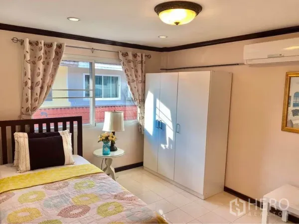 联排别墅 出租或出售在Prawet, Bangkok - 明亮卧室，单人床、白色衣柜、空调与带窗帘的大窗。