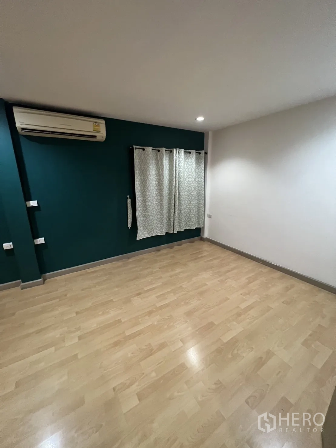 Townhouse for rent in Watthana, Bangkok - Bedroom corner with teal wall, air-conditioning and light wood floors.