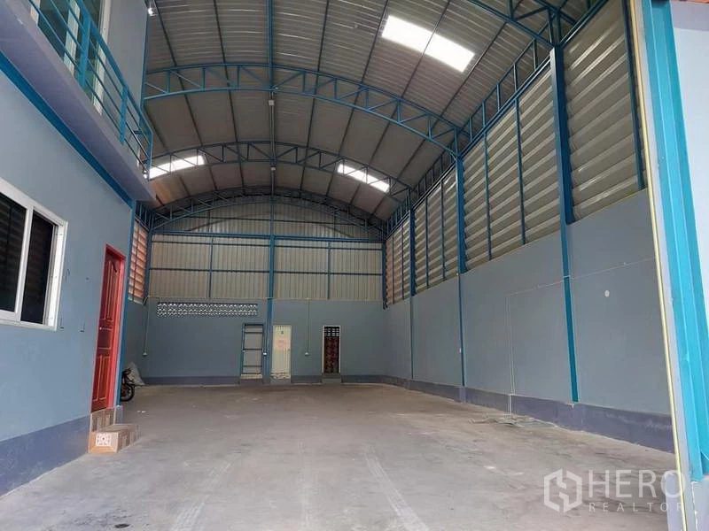 Warehouse for rent or sale in Bang Bua Thong, Nonthaburi - Wide interior bay with high ventilated walls and roll-up doors at the rear.