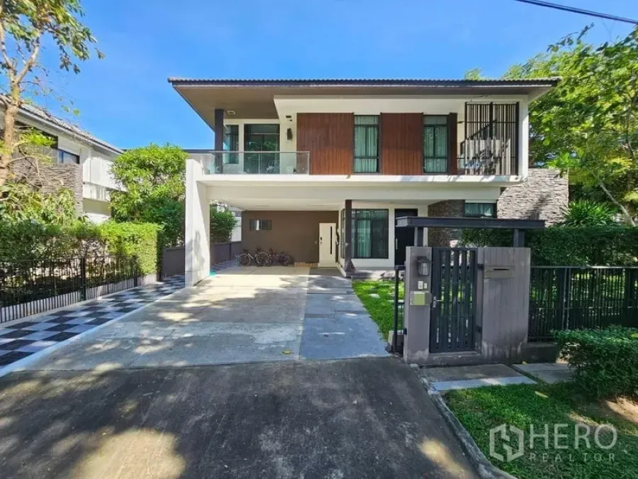 Detached House for sale in Prawet, Bangkok - Front elevation of the two‑storey home with wide driveway, gate and landscaped lawn.