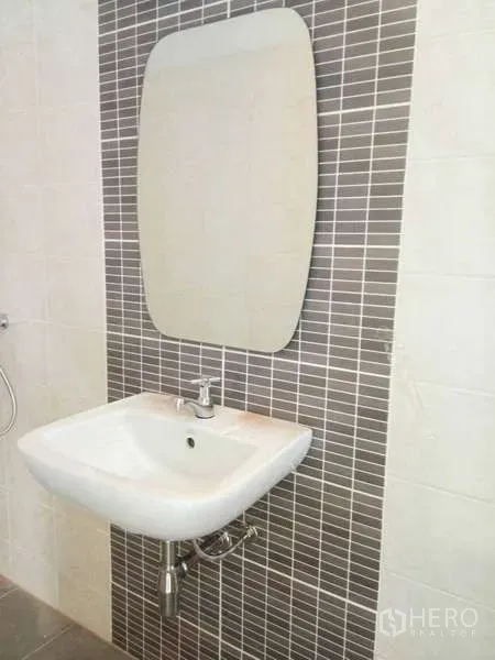 Shophouse for rent in Bang Na, Bangkok - Bathroom corner featuring a wall-mounted sink, mirror and tiled accent wall.