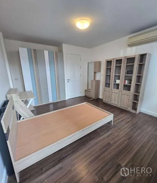 Townhouse for sale in Watthana, Bangkok - Spacious bedroom with wood floors, wardrobes and shelving, plus air conditioning.