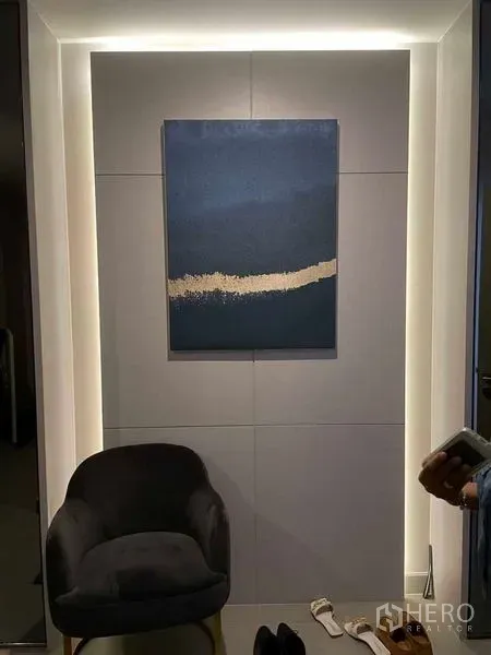 Condominium for rent in Pathum Wan, Bangkok - Entry niche with accent lighting and a blue modern artwork above a chair.
