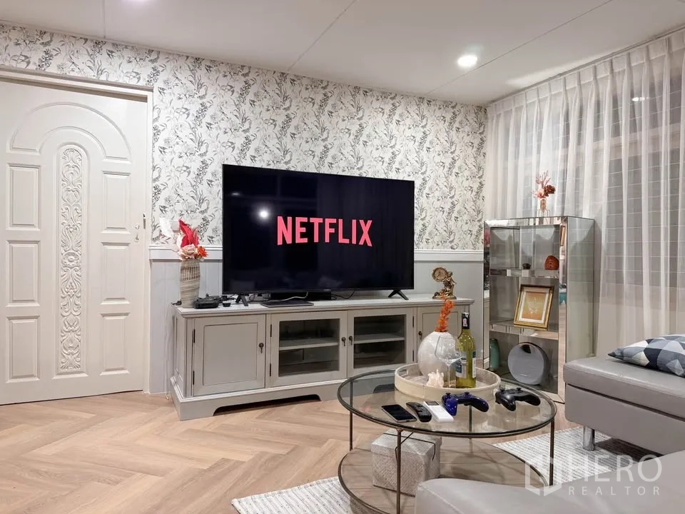Detached House for rent in Huai Khwang, Bangkok - Family lounge with large flat-screen TV and floral feature wall.