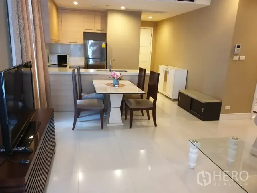 Condominium for rent in Khlong Toei, Bangkok - Open-plan dining and kitchen with island sink, light wood cabinets, and stainless refrigerator in a modern Bangkok condo.