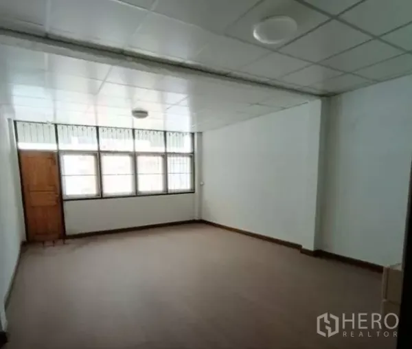 Shophouse for rent in Bang Rak, Bangkok - Bright room with grid windows, drop ceiling and wood-look flooring.