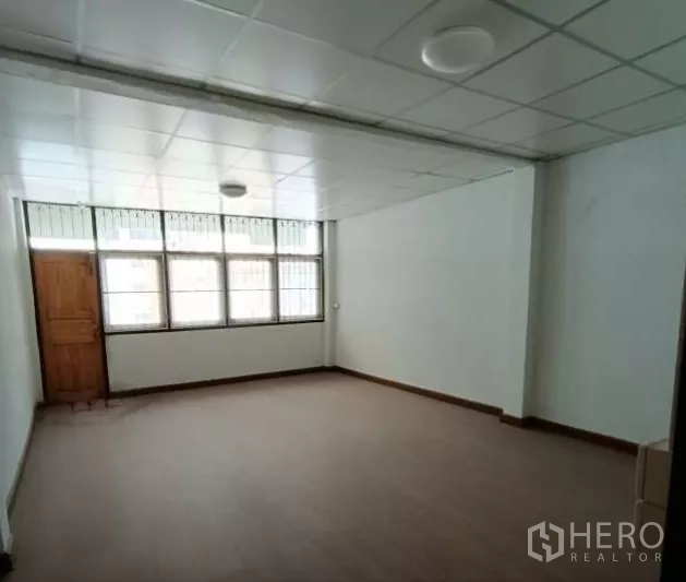 Shophouse for rent in Bang Rak, Bangkok - Bright room with grid windows, drop ceiling and wood-look flooring.