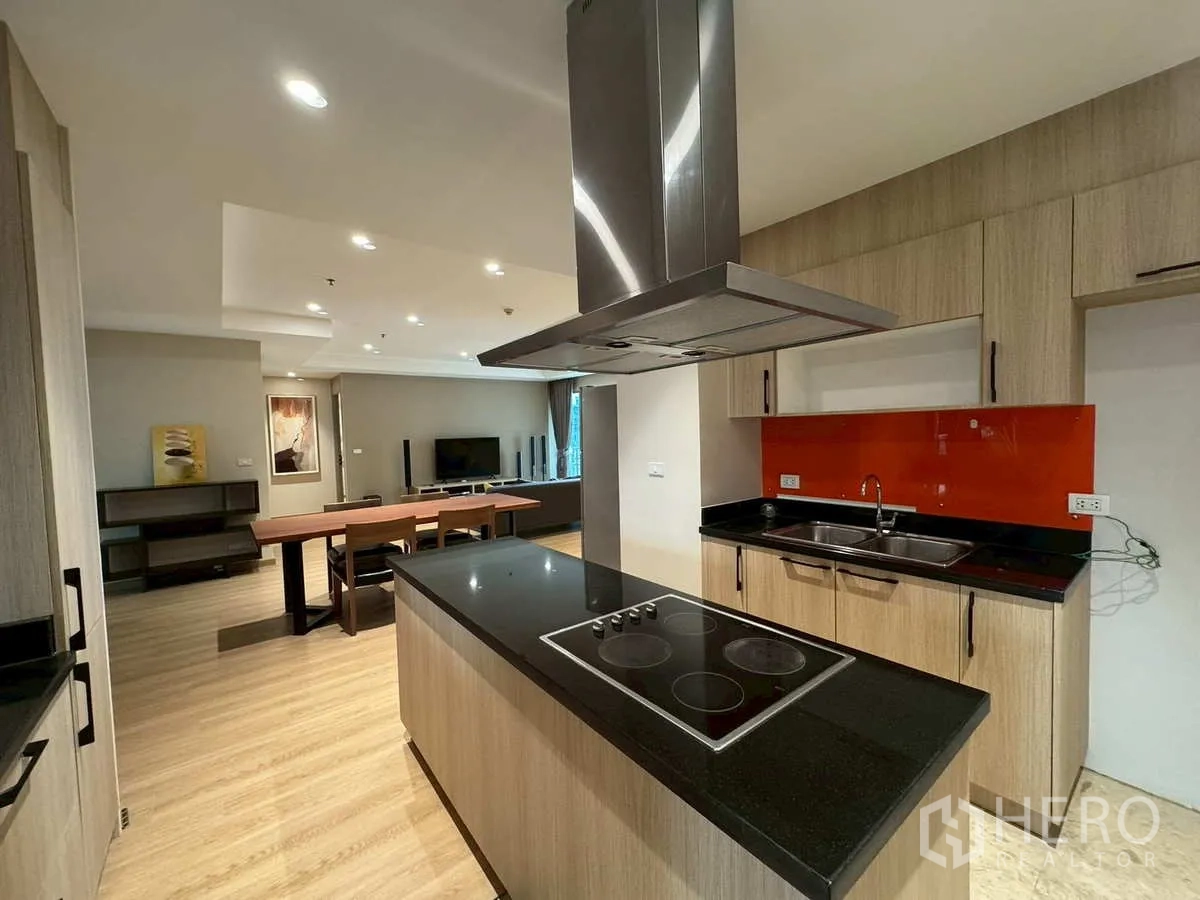 Condominium for rent or sale in Khlong Toei, Bangkok - Modern kitchen with island cooktop, range hood and double sink.