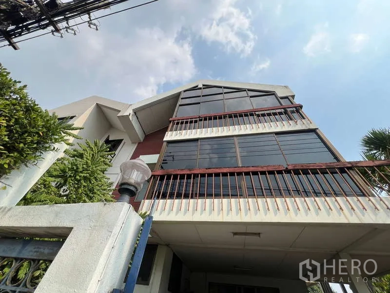 Detached House for sale in Suan Luang, Bangkok - Multi-storey detached house with large glass gable facade and balconies in Suan Luang under blue sky.