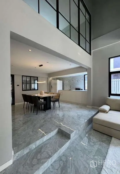 Townhouse for rent or sale in Prawet, Bangkok - Open-plan living and dining on glossy marble floors with steps.