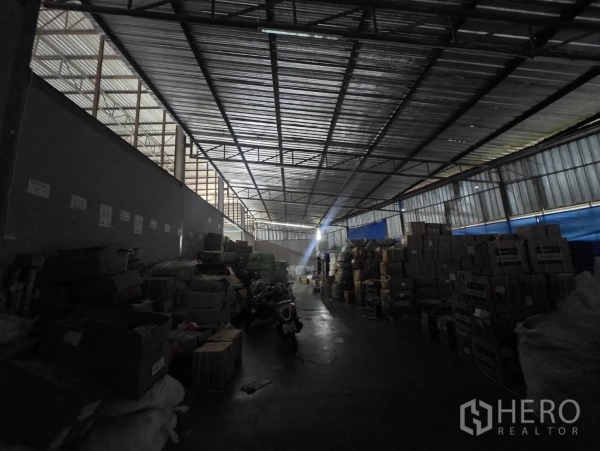 Factory for rent or sale in Mueang Samut Sakhon, Samut Sakhon - Warehouse bay used for storage with stacked cartons under metal roof structure.
