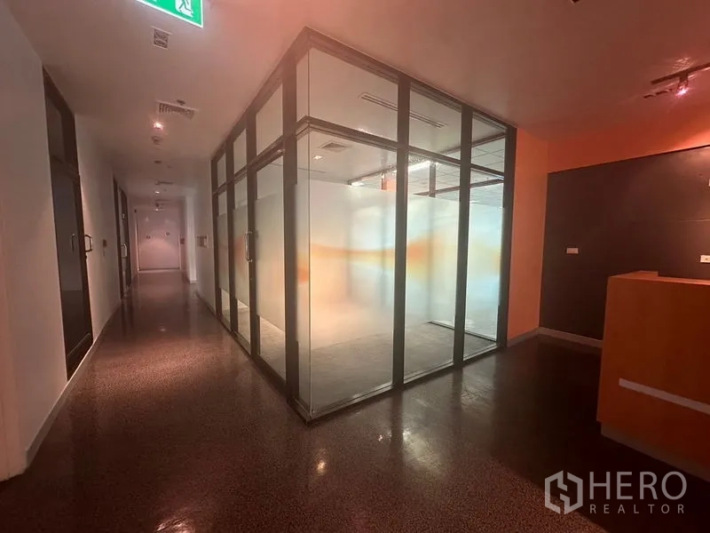 Office Space for rent in Khlong Toei, Bangkok - Hallway featuring a glass-walled meeting room with frosted panels and an exit sign.