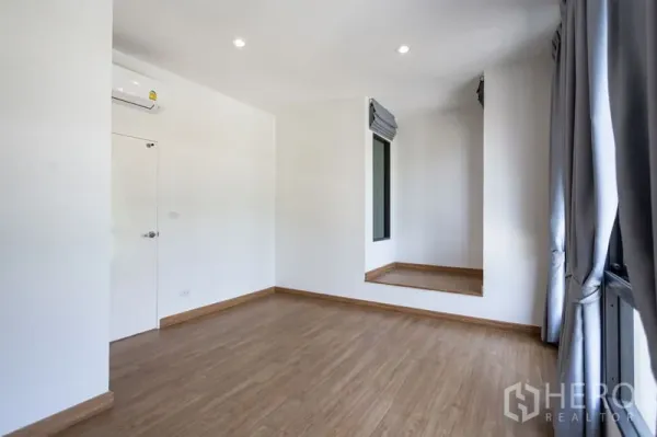Townhouse for rent in Bang Phli, Samut Prakan - Bedroom with wood floors, air conditioning, large windows and a raised window nook.