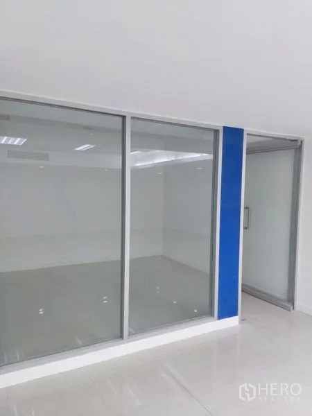 Office Space for rent in Chatuchak, Bangkok - Close-up of a glass-partitioned room with sliding door and blue accent column.